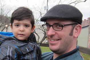 Father holding child outdoors, smiling